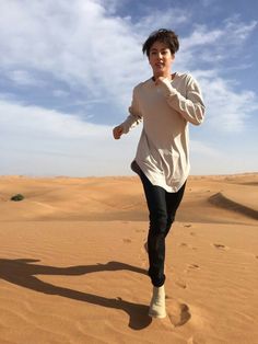 This contain BTS Jin running across a sandy field