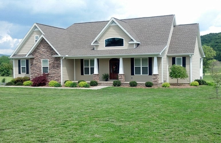 Front exterior view with gable rooflines, stone accents, and a deep covered porch framed with tapered columns.