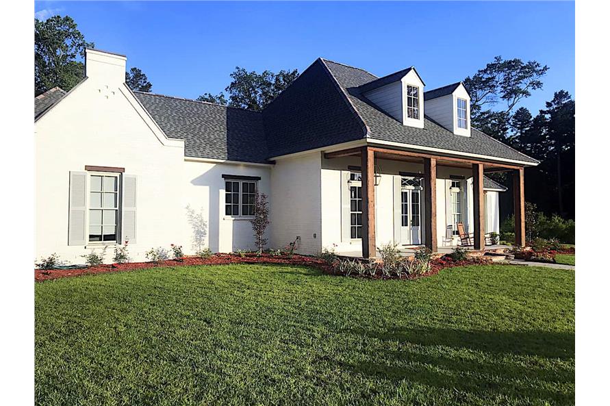 The covered porch is framed with wooden posts and topped with twin dormers.