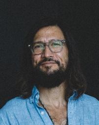 A person with long hair and beard wearing glassesDescription automatically generated