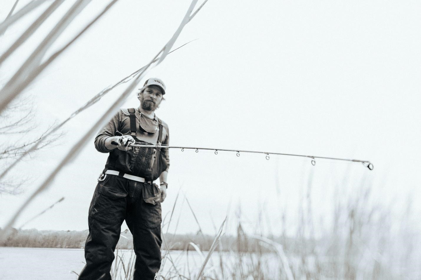 a man standing next to a body of water holding a fishing pole