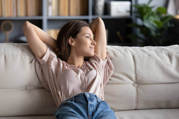 Relaxed woman lounging on a couch, reflecting the calming effects of lowered cortisol after using stress-reducing supplements.