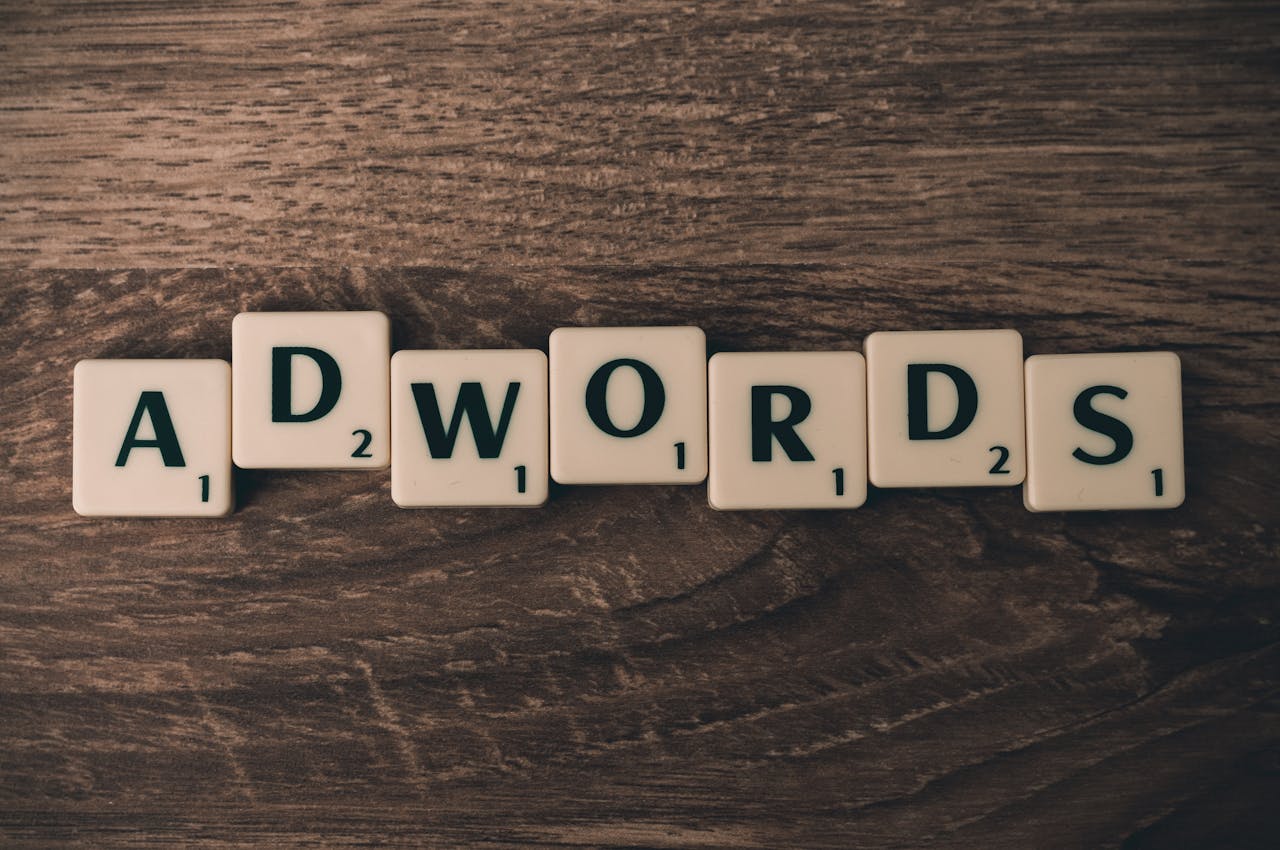 Scrabble tiles spelling 'Adwords' on a wooden surface, a tool to promote your business locally through targeted advertising.