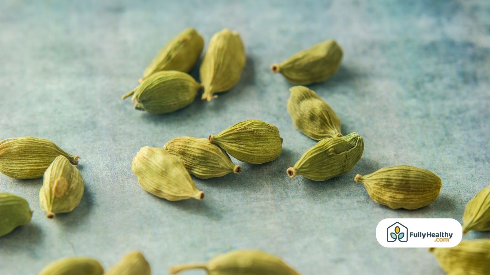 Scattered green cardamom pods on a blue textured background