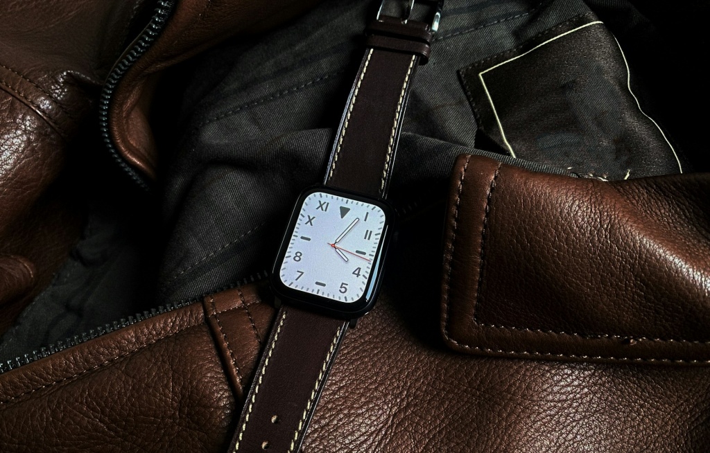 Apple Watch with leather strap on a brown leather jacket