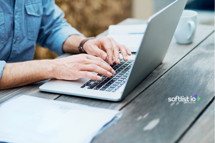 A person typing on a laptop at an outdoor table.