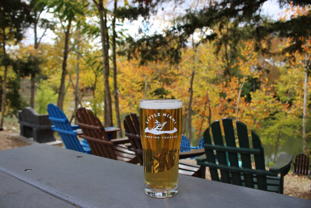 A glass of craft beer from Little Miami brewing company set against a scenic view.