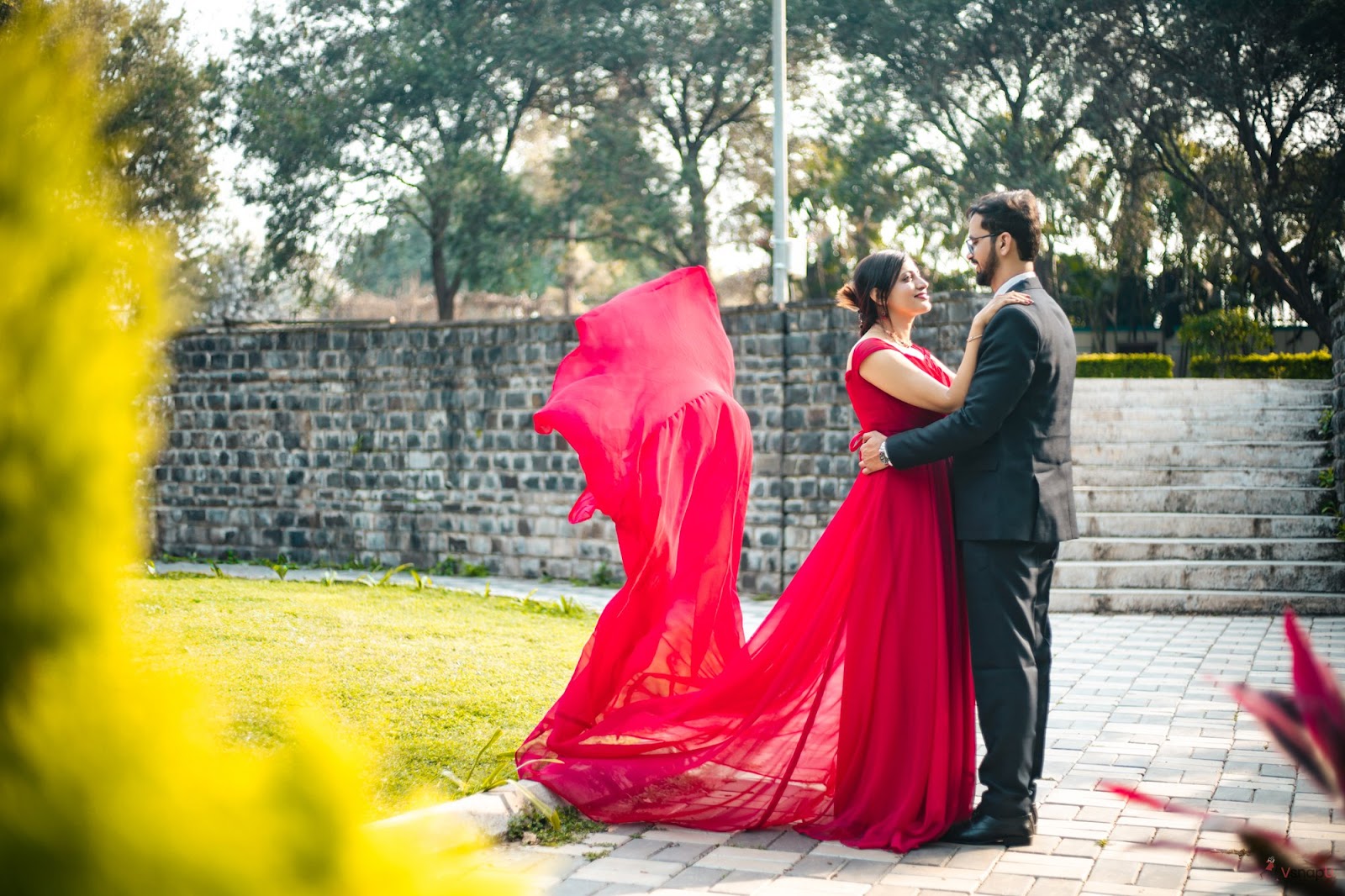 Romantic pre-wedding photography of a couple dressed in formal attire amidst lush garden greenery