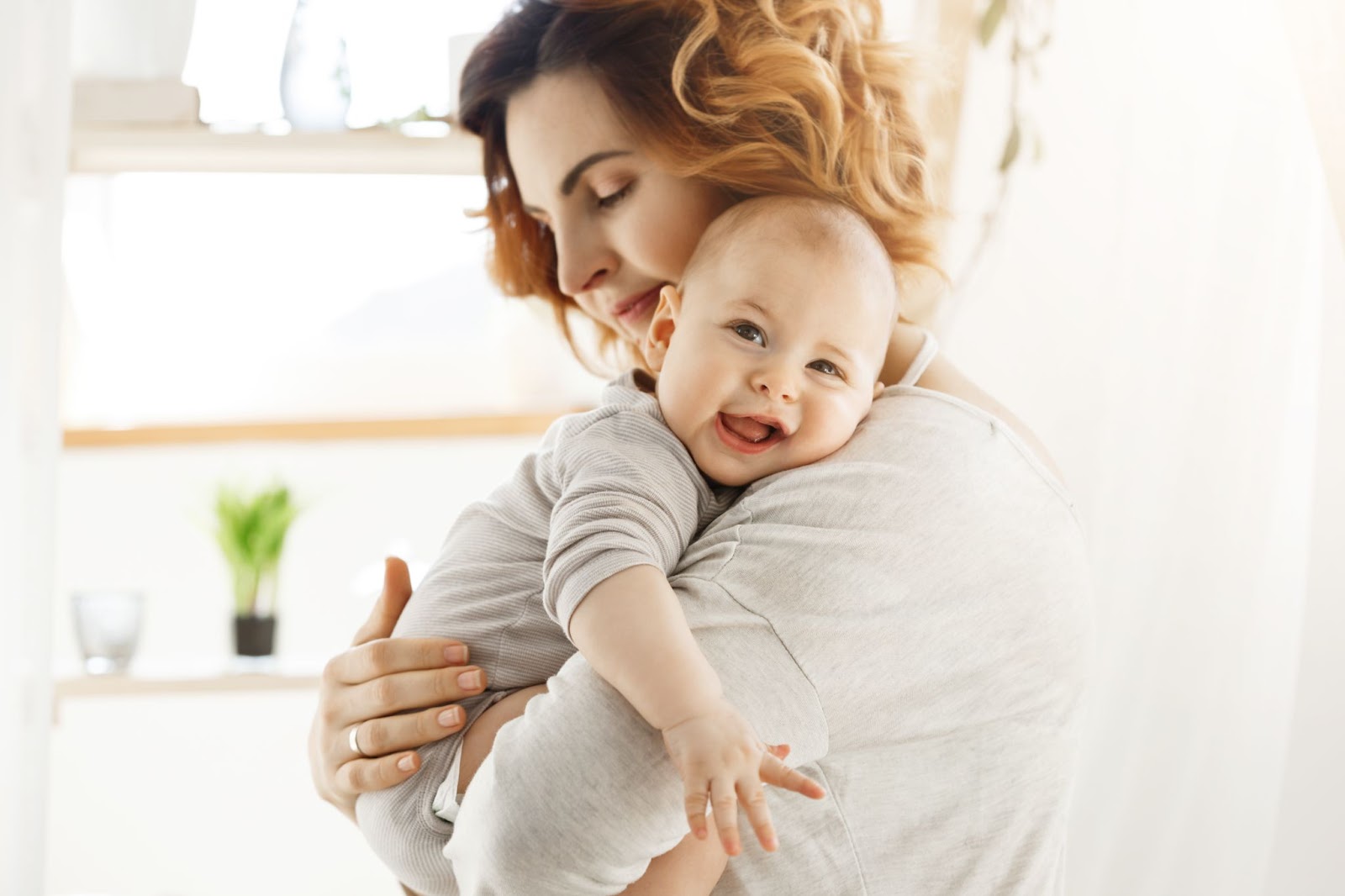 A mom is seen holding her happy baby in her hands, following the best tips for new parents.