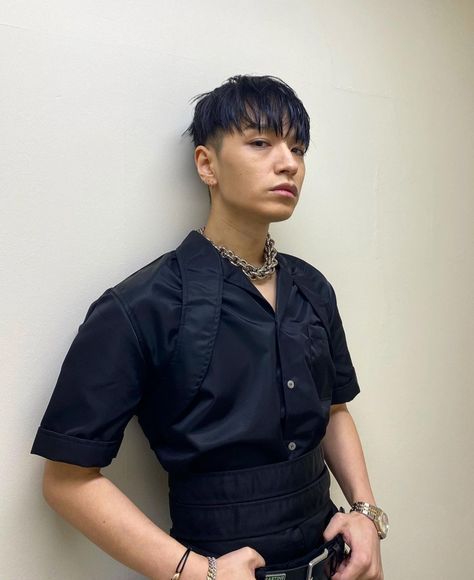 This contain Simon Dominic is standing against a wall with his hands in his pockets