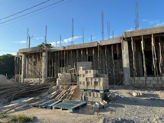 A building under construction with pallets and a blue sky

Description automatically generated