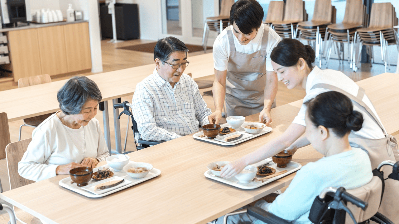 介護施設で職員が利用者に食事を提供している様子