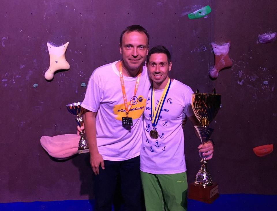 Two men holding trophies posing for a photo

Description automatically generated