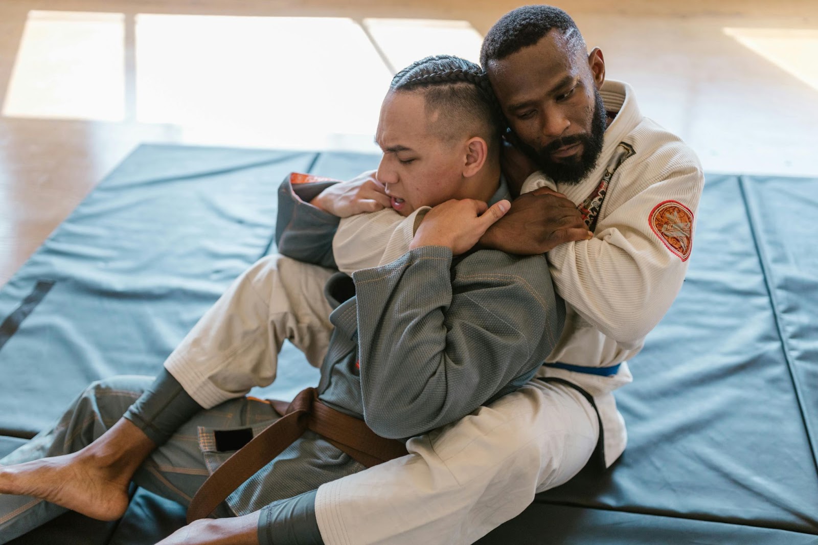 A martial arts instructor demonstrating a rear chokehold on a student