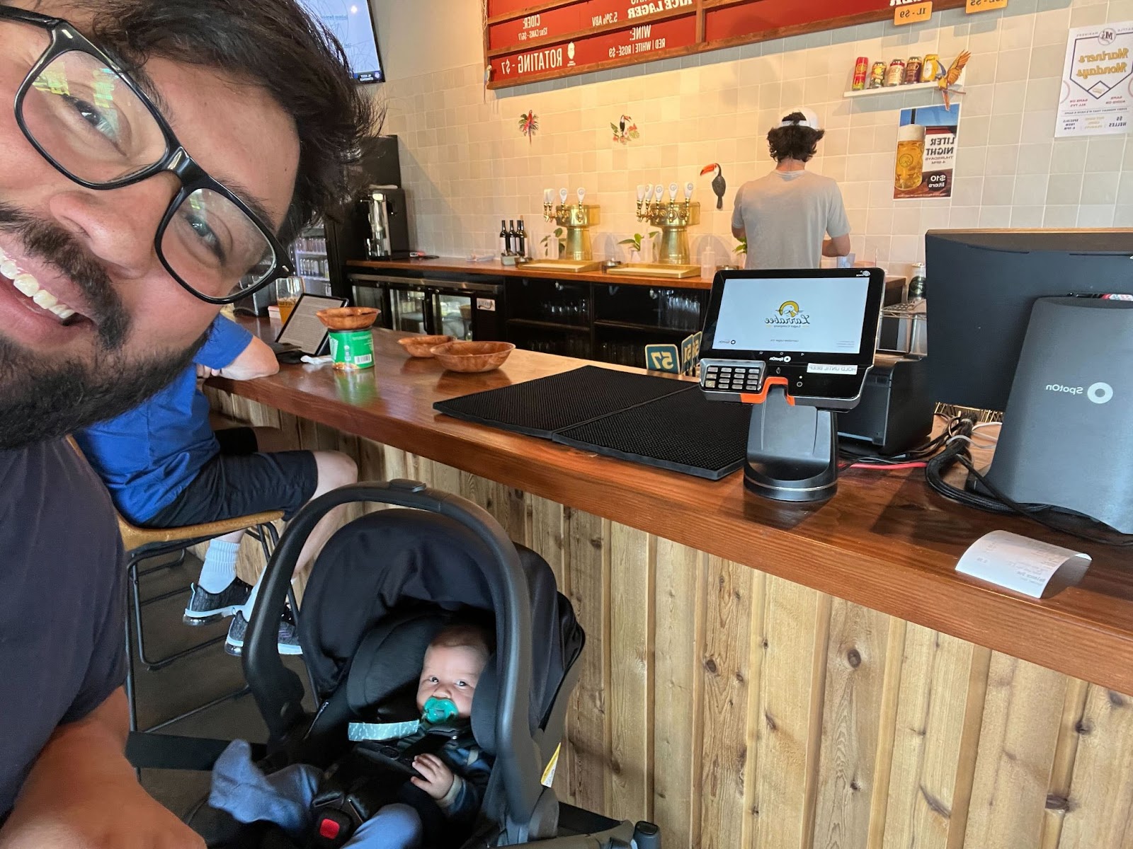 Rudy and his newborn baby posing with SpotOn restaurant point of sale in a restaurant.