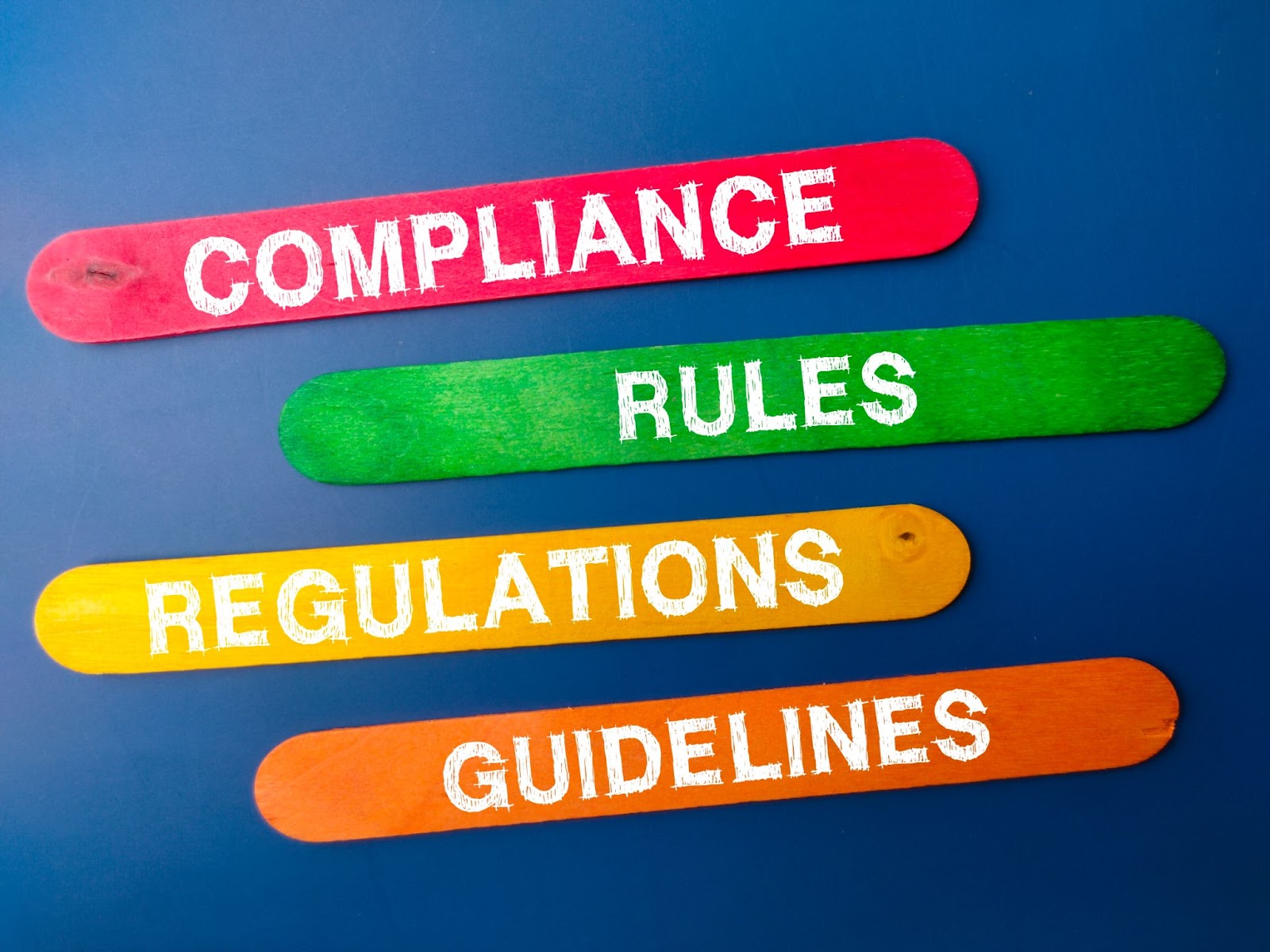 Colorful ice cream sticks labeled "compliance," "rules," "regulations," and "guidelines" symbolize the various aspects of compliance in business risk management.