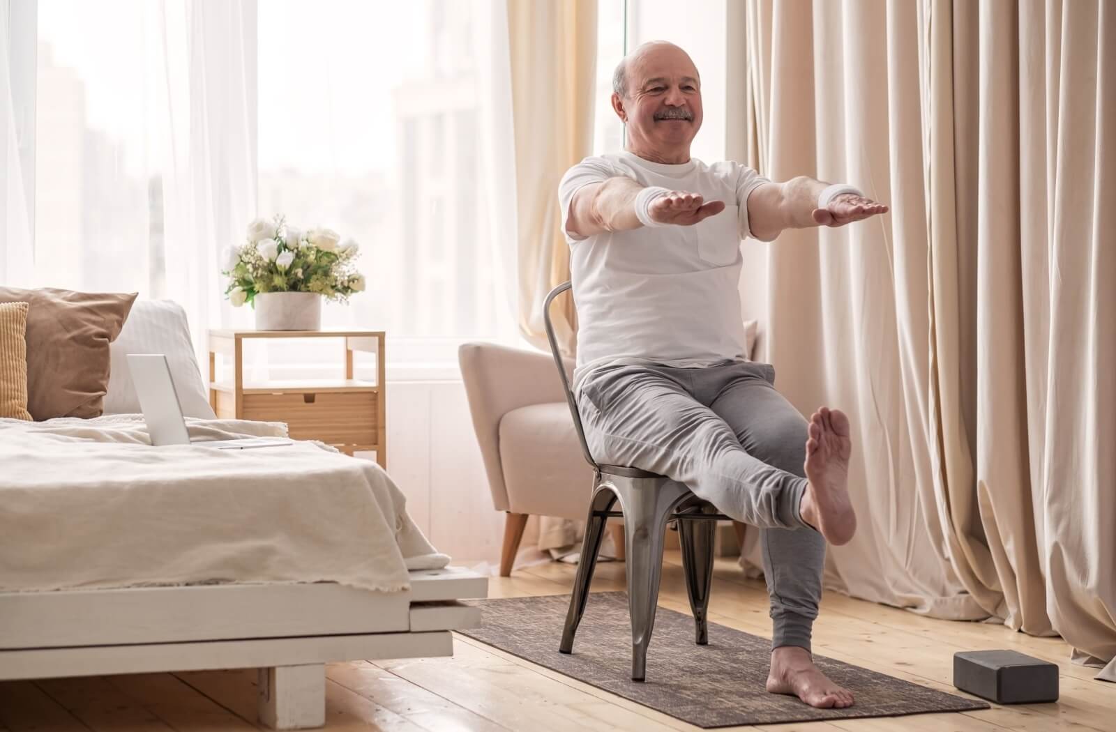 An older adult does a modified version of the standing leg lift from a seated position.