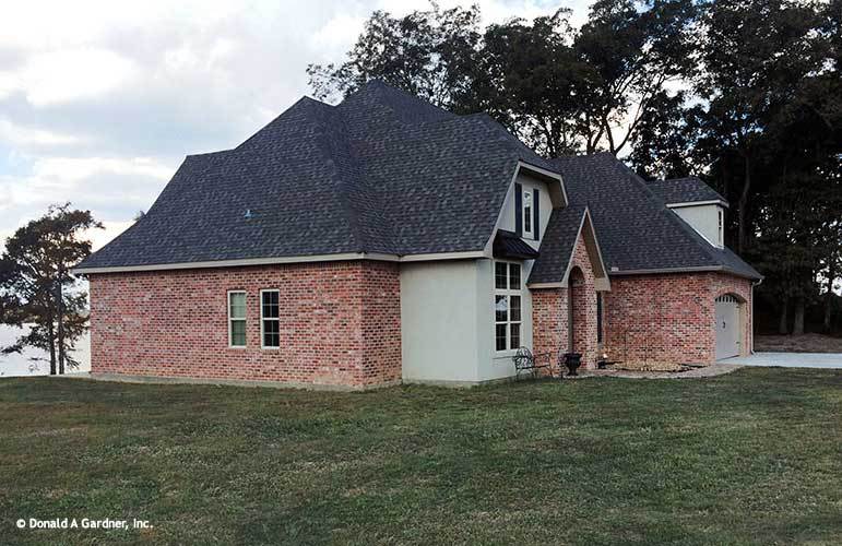 Left exterior view showing the red brick cladding, hipped rooflines, and a gabled entry.