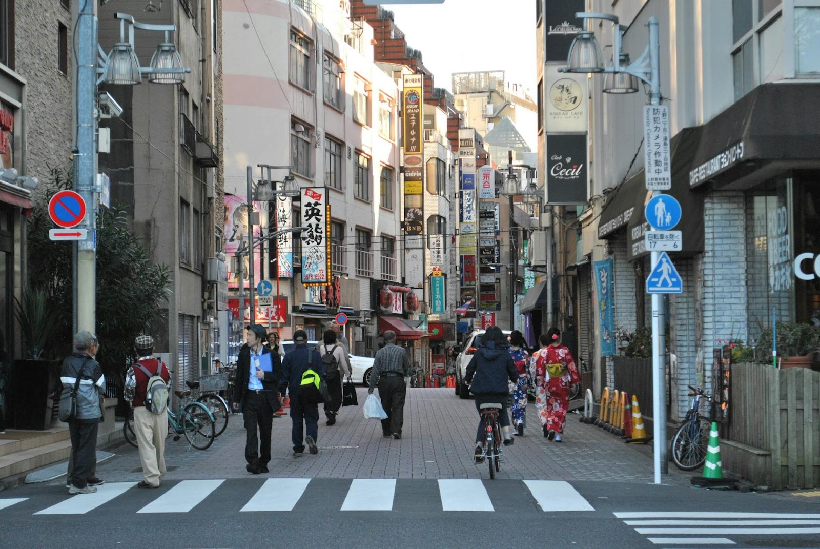 Vibrant Tokyo street scene with pedestrians, traditional clothing, and colorful storefronts.