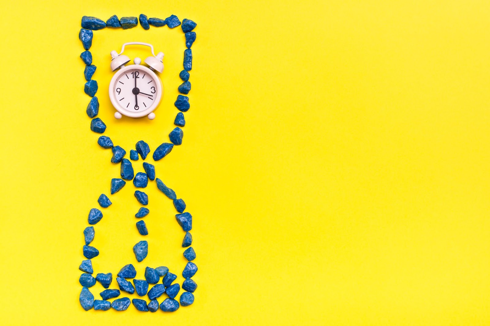 Clock with stones shaped like an hourglass around it. 