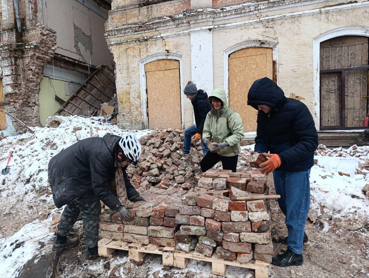 A group of people building a pile of bricks

Description automatically generated