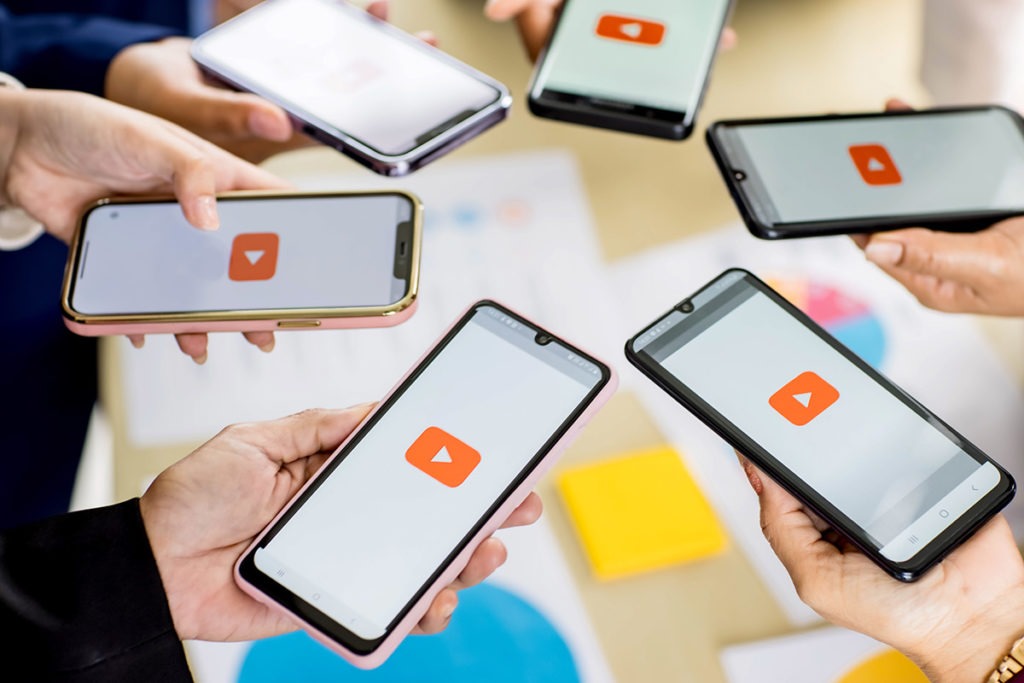 Six hands holding screens displaying the YouTube logo, representing YouTube addiction.