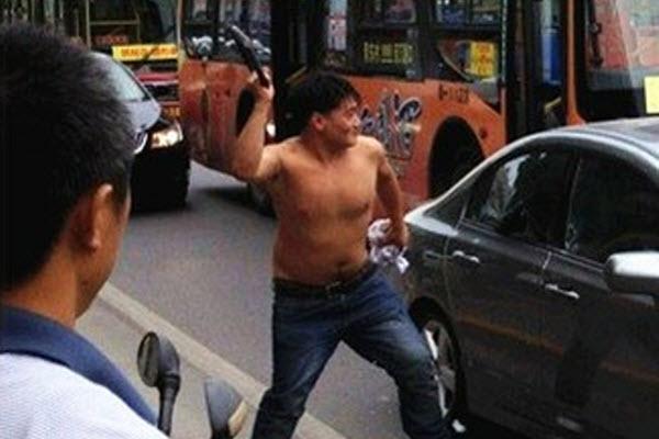 A shirtless Chinese man attacks a Toyota Corolla with a metal u-lock during anti-Japan demonstrations in Xi'an, China.