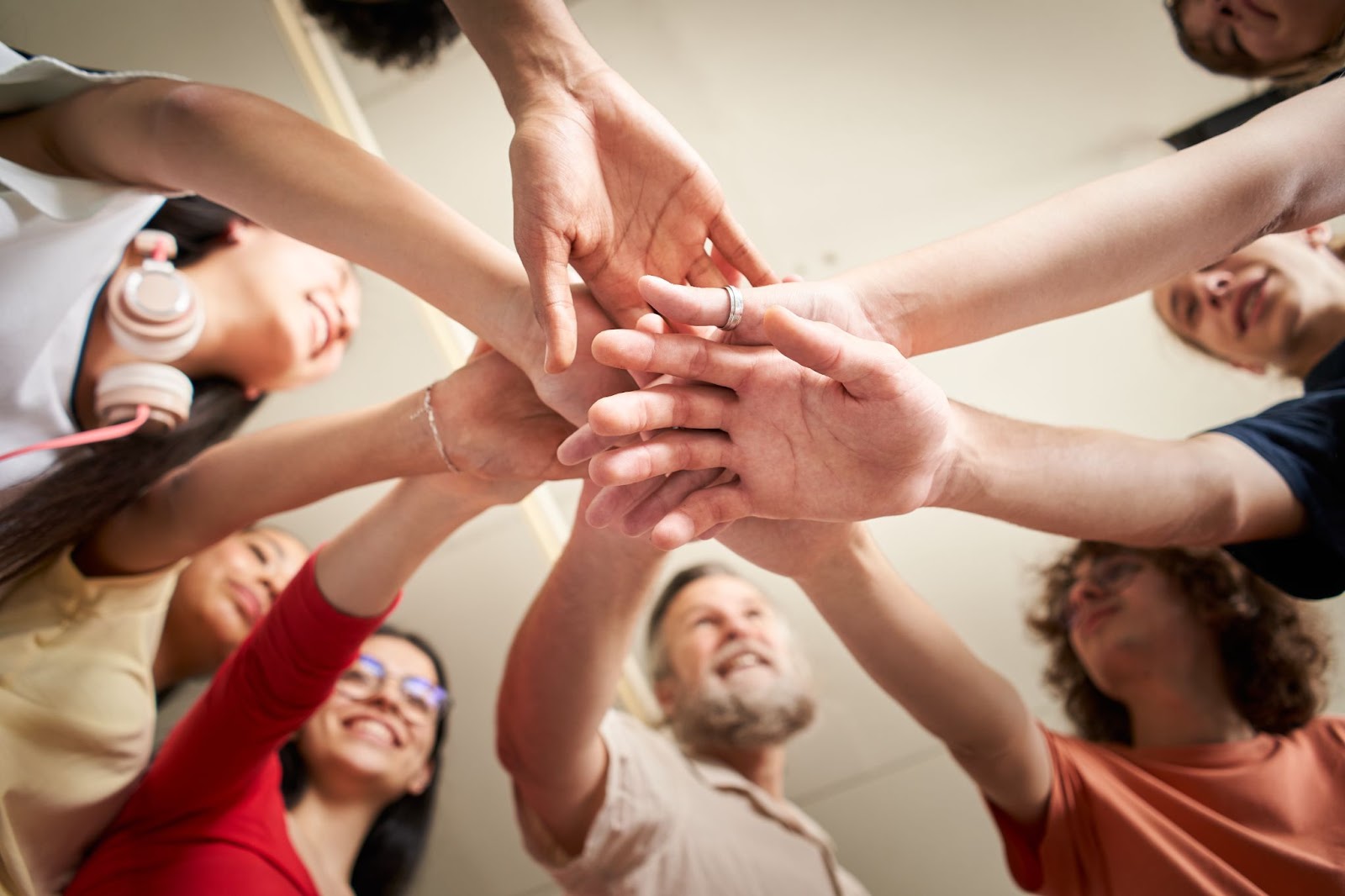 Men and women with their hands overlapping in the center. 