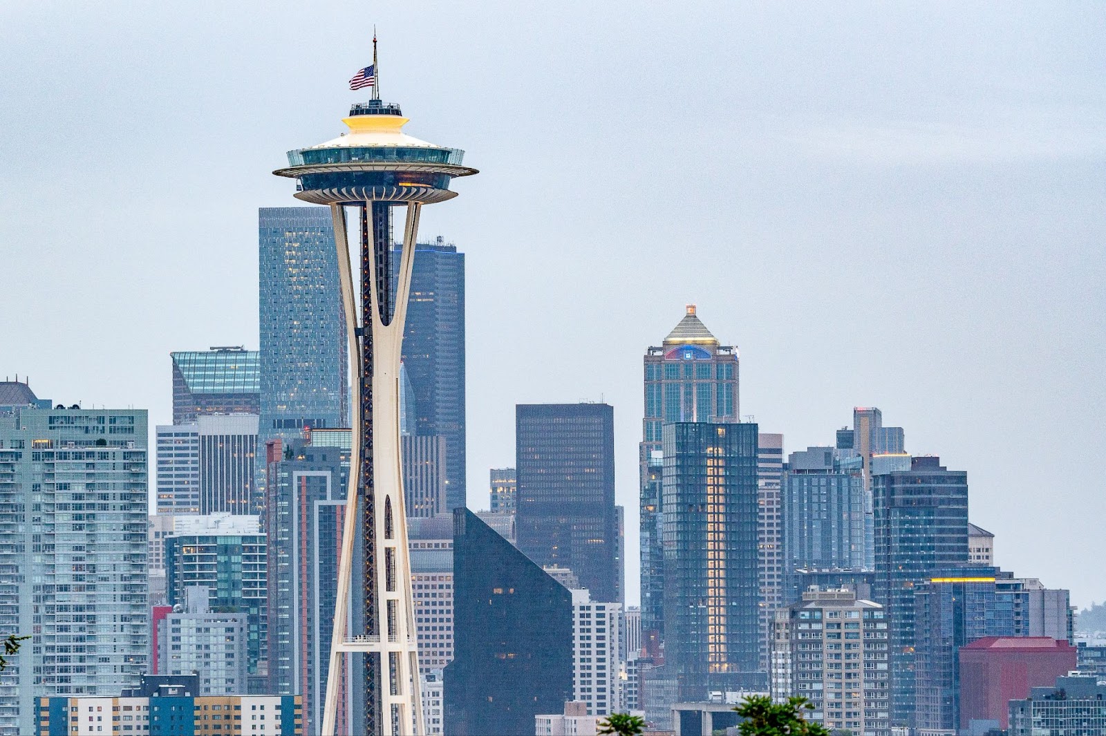 Photo of the space needle with an American flag on top, the city of Seattle behind