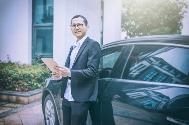 Business men use tablet computers next to cars