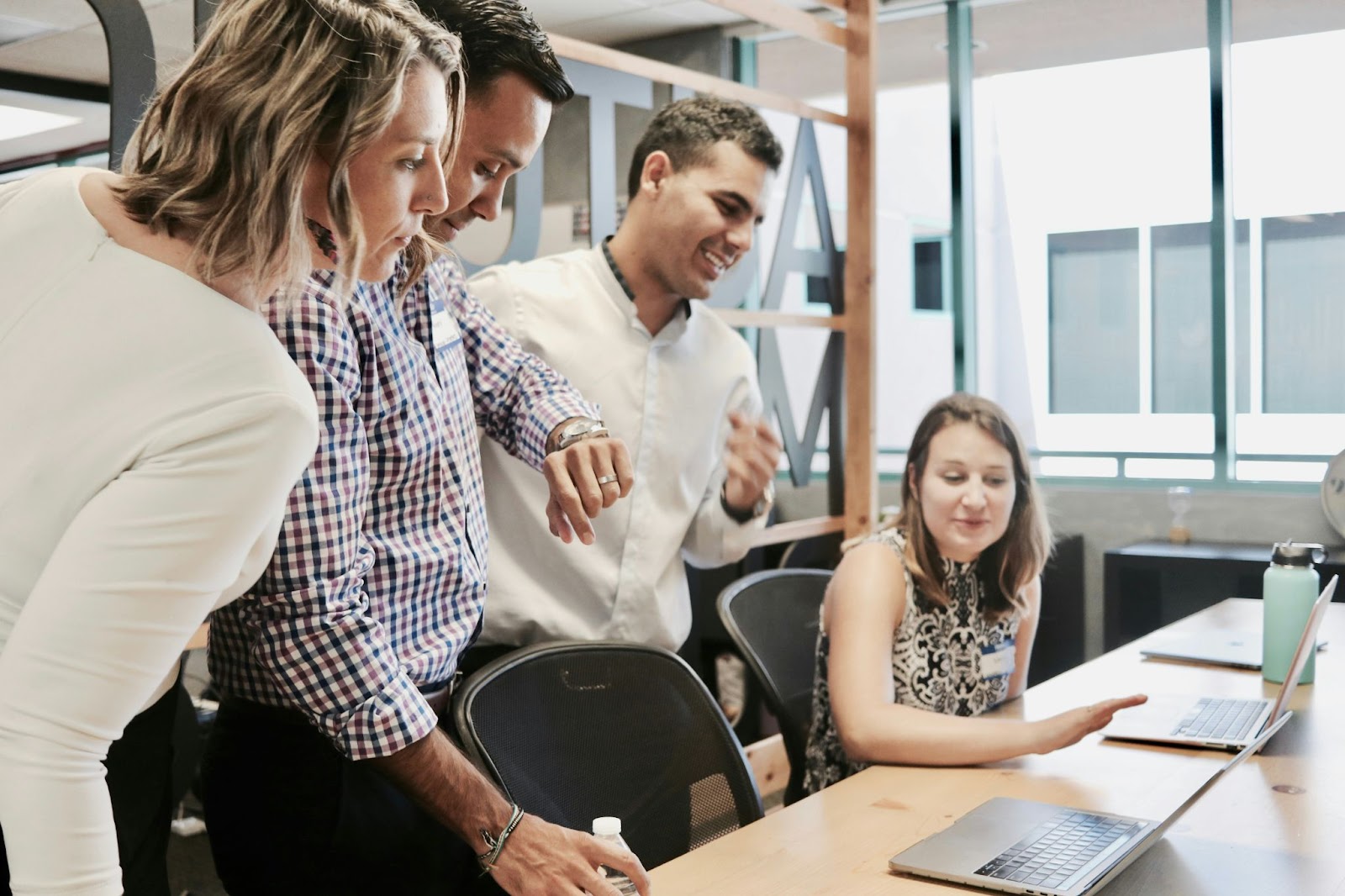 people in an office by a laptop