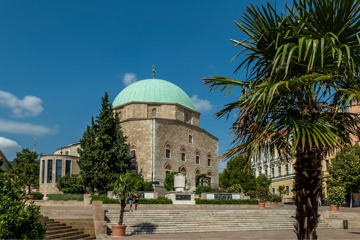 It's stone build masjid and trees around it and people are wandering through it