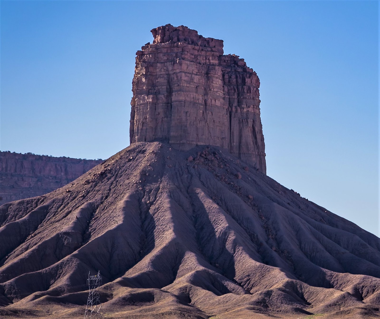 Chimney Rock rising above rocky land with a clear sky in the background.