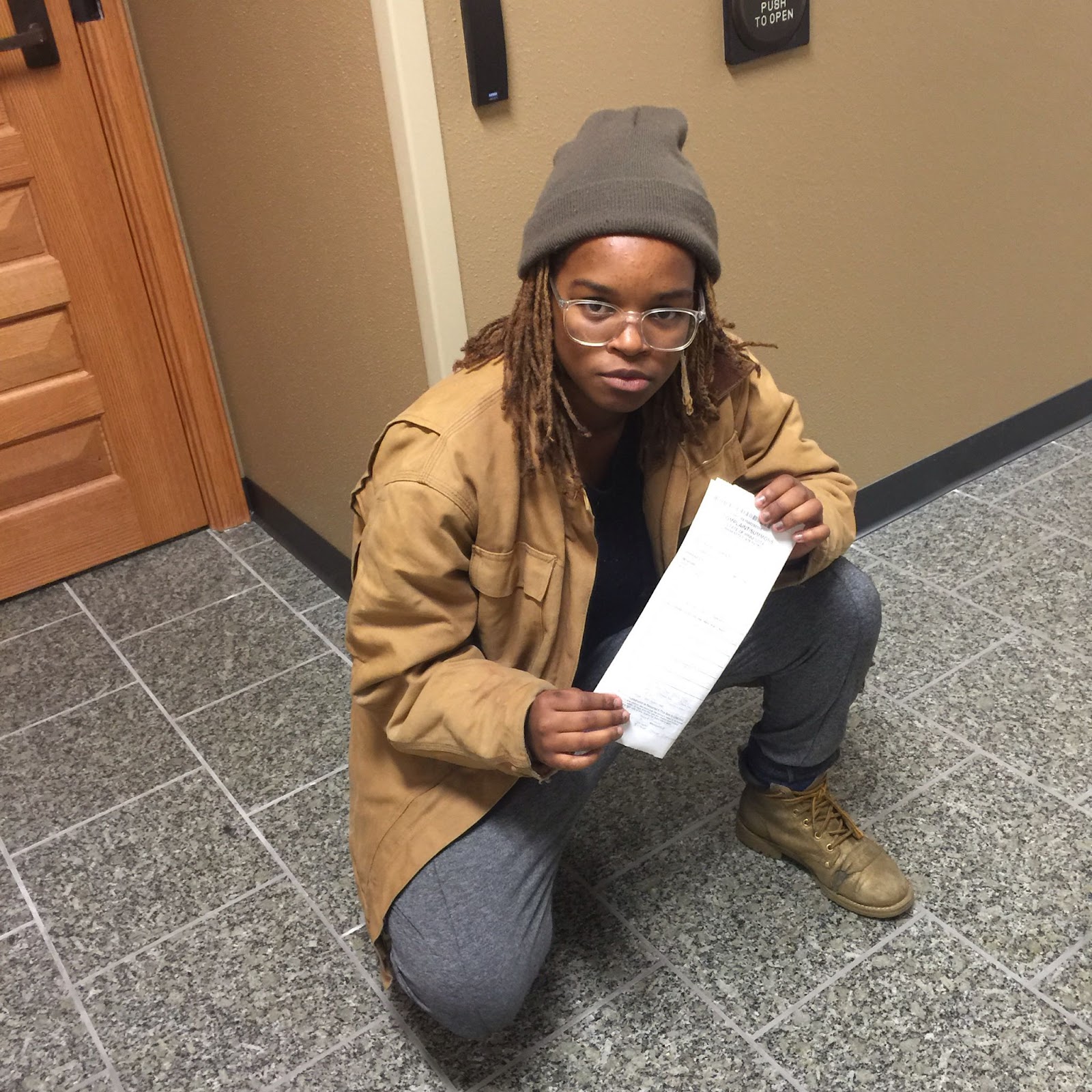 Image: Yonci posing down on one knee with the arrest ticket at the juvenile detention center downtown, 2015. Photo by the author.