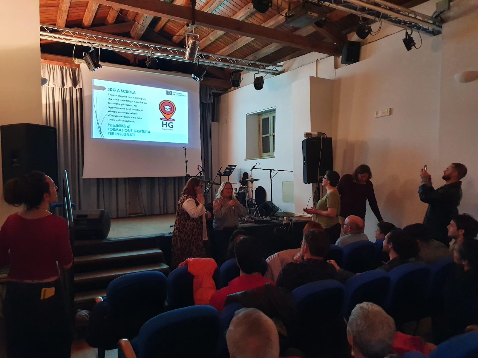 A group of people in a room with a projector screen

Description automatically generated