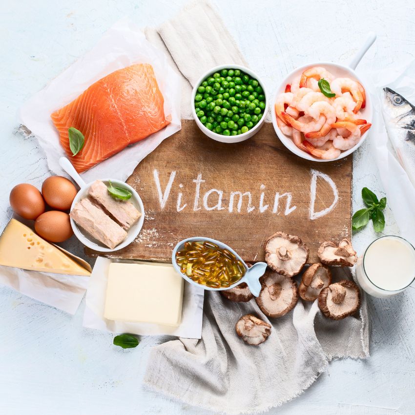 A wooden board displaying vitamin D-rich foods like salmon, eggs, and mushrooms.