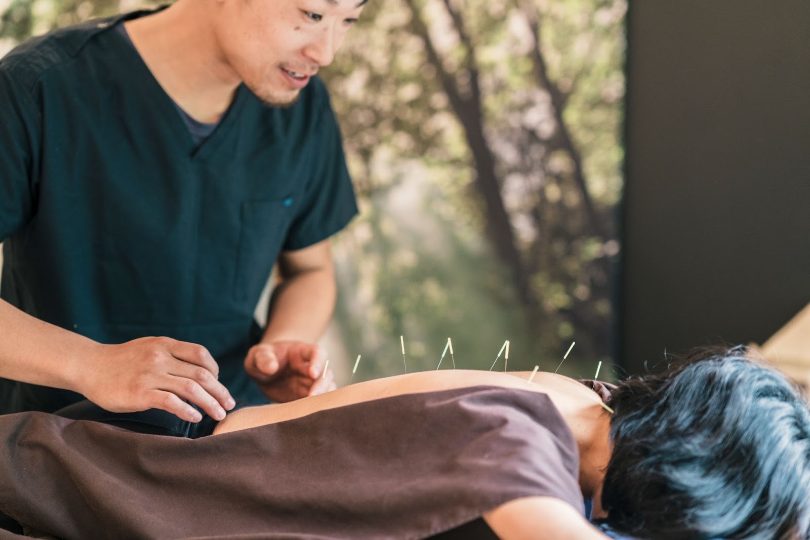 Man using acupuncture needles on a woman’s back. 