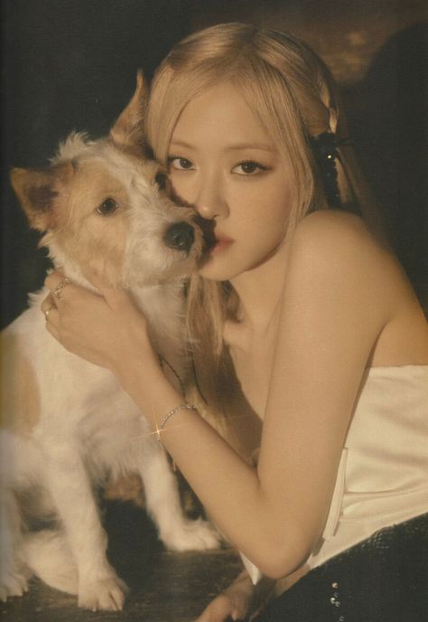 This contains an image of BLACKPINK's Rosé  holding a small dog in her lap and posing for a photo with it's face close to the camera