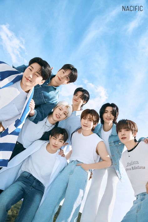 This contains an image of ATEEZ
 group standing next to each other in front of a blue sky