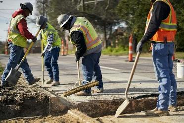 A group of construction workers using shovels

Description automatically generated