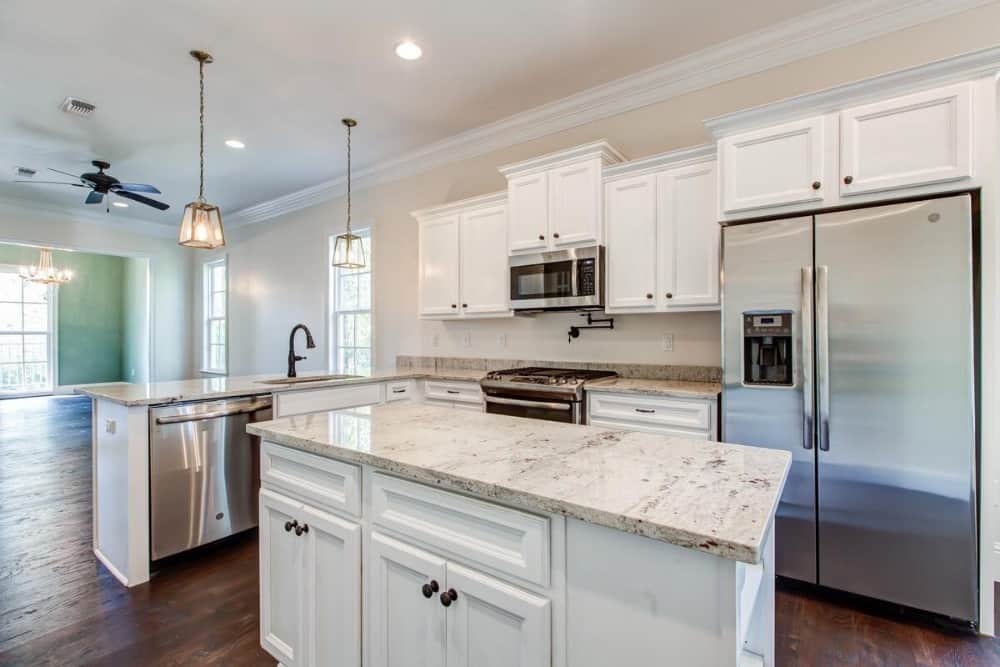 The kitchen offers white cabinetry, granite countertops, a center island, and a peninsula fitted with a sink and dishwasher.