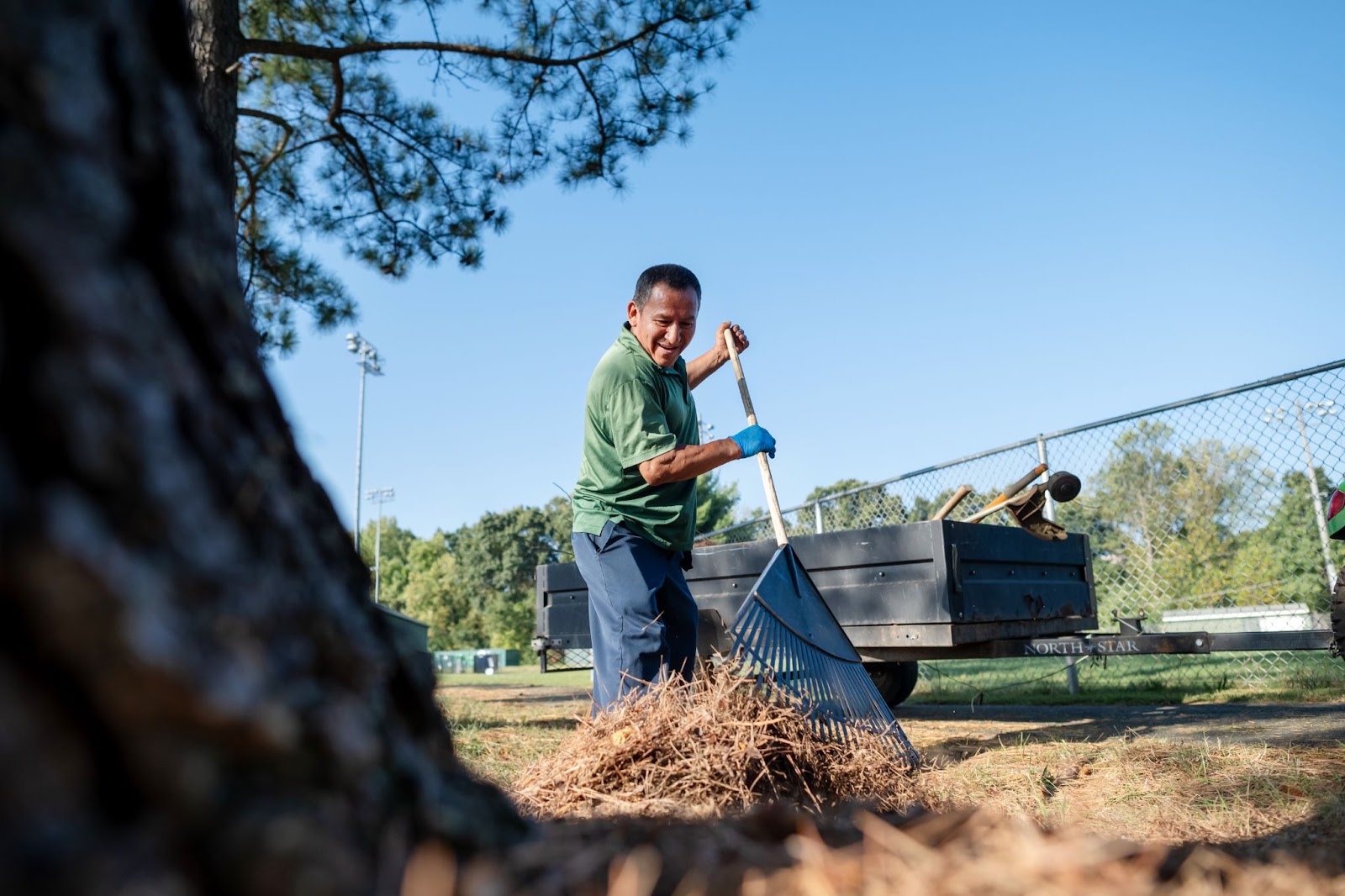 A custodian works outside, raking