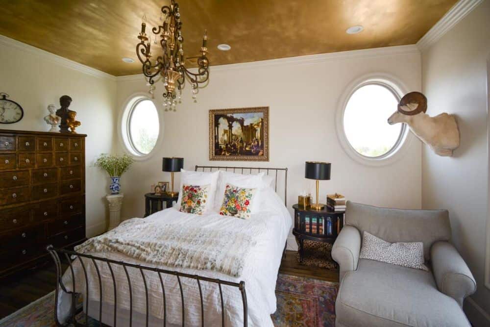Family bedroom with a metal bed, a gray lounge chair, and round windows.