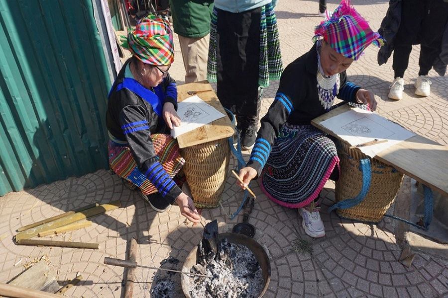 Mong women draw on fabric put on a Lu Co