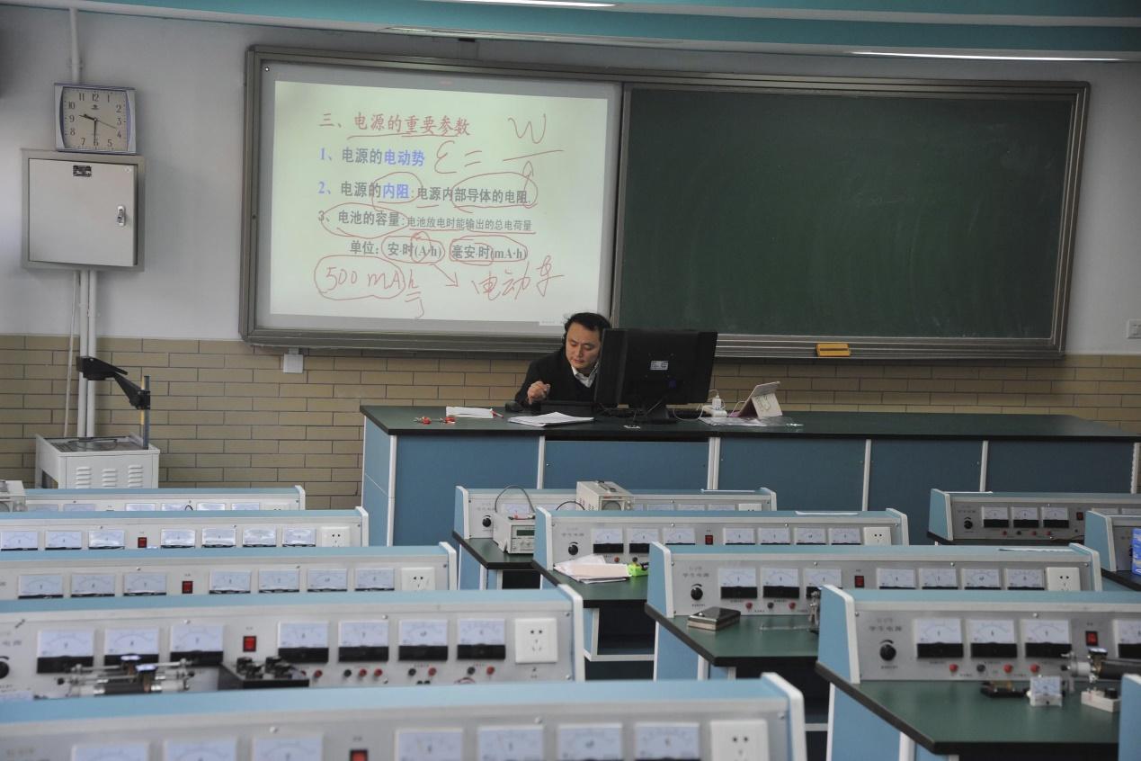Physics teacher Wu Guangguo sits in an empty laboratory as he teaches a class during an online course at Jingshan School, on a smoggy day under a "red alert" for air pollution, in Beijing, China, December 21, 2015. Schools are recommended to close and outdoor construction is banned under "red alert" for smog. REUTERS/China Daily ATTENTION EDITORS - THIS PICTURE WAS PROVIDED BY A THIRD PARTY. THIS PICTURE IS DISTRIBUTED EXACTLY AS RECEIVED BY REUTERS, AS A SERVICE TO CLIENTS. CHINA OUT. NO COMMERCIAL OR EDITORIAL SALES IN CHINA.