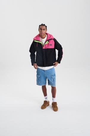 Homem em pé com blusa preta e rosa