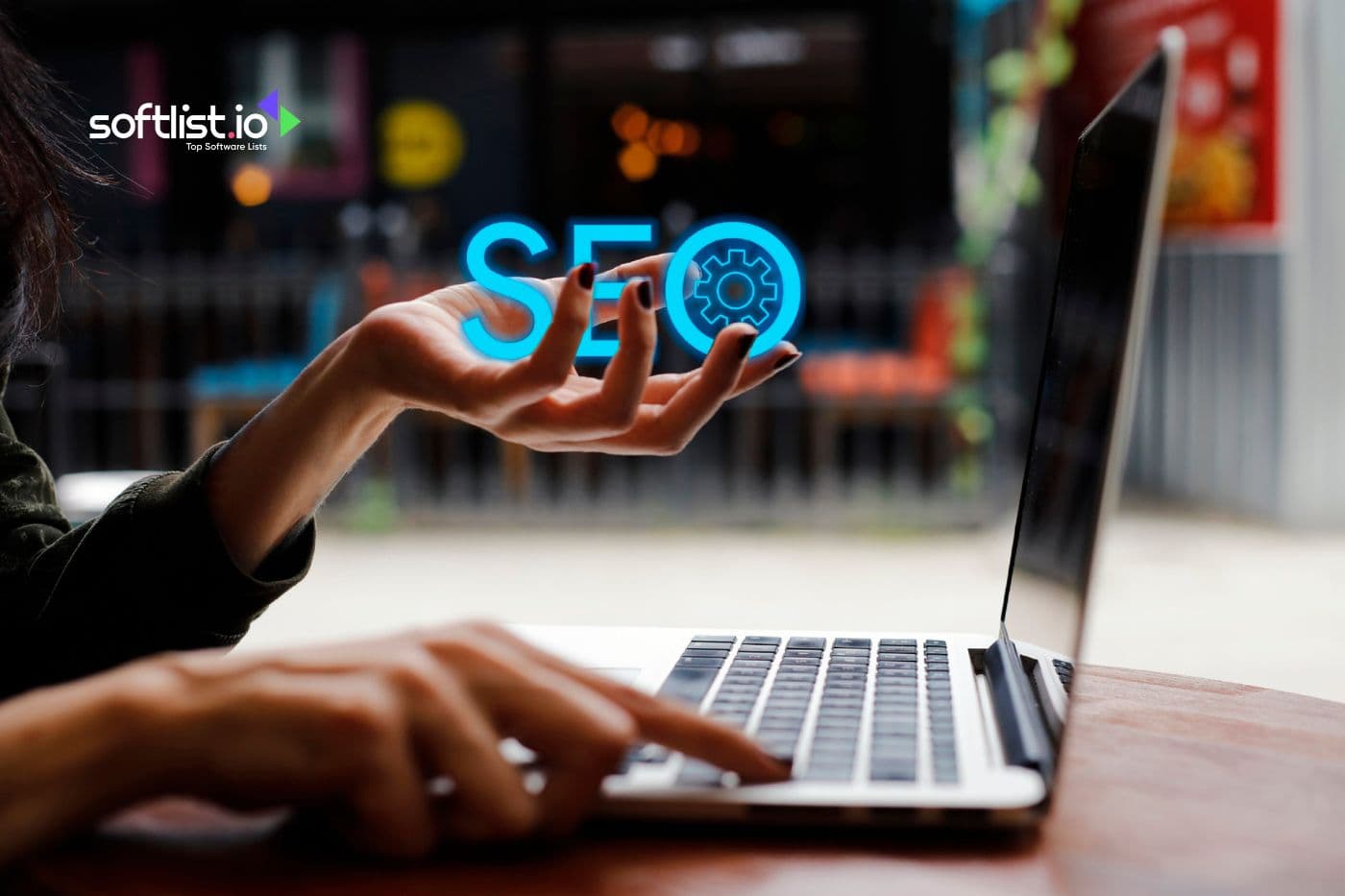 Hand holding 'SEO' icon above a laptop, indicating online optimization services.