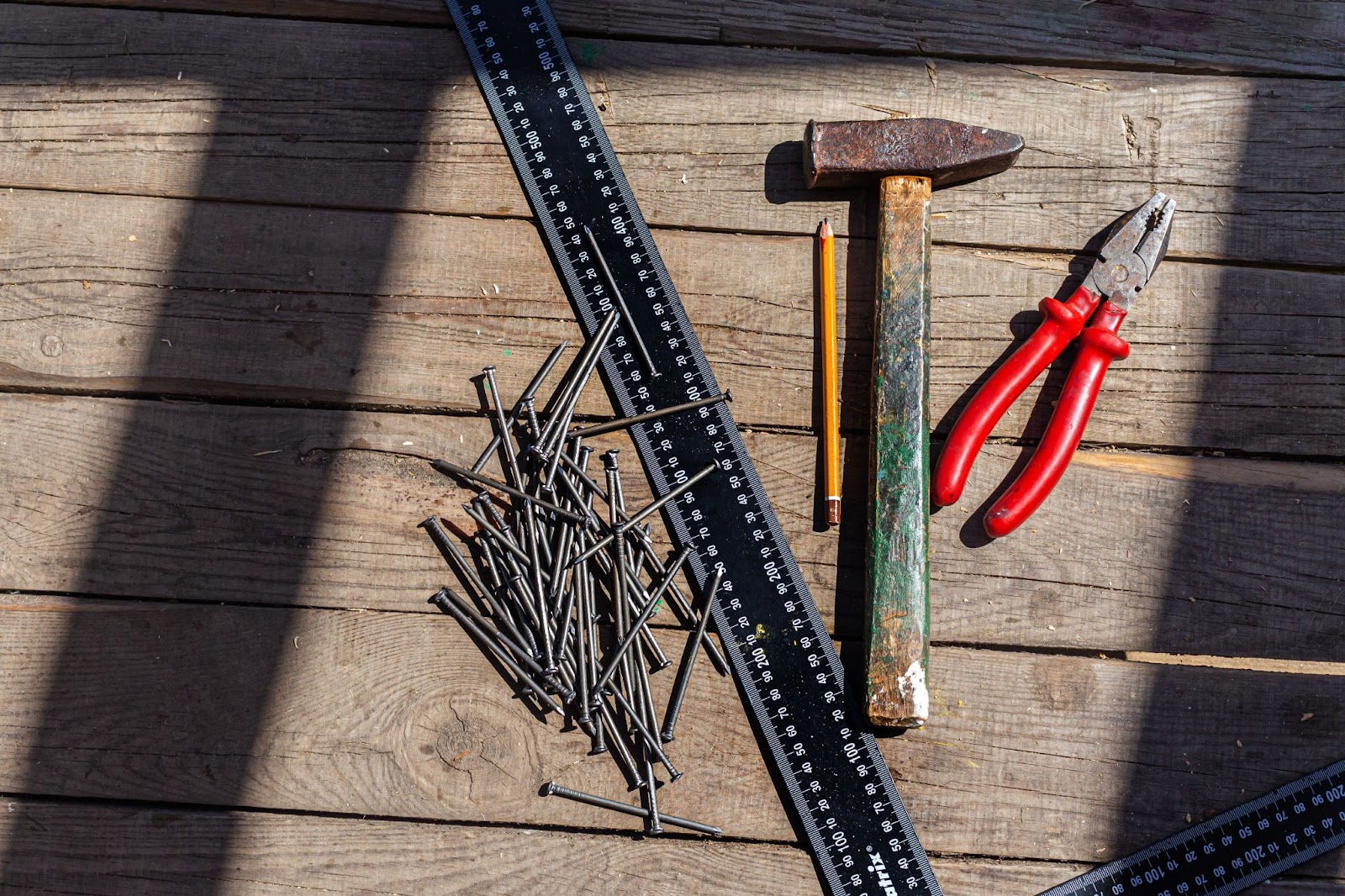 Hammer, ruler, nails, and other materials on a wooden surface. 