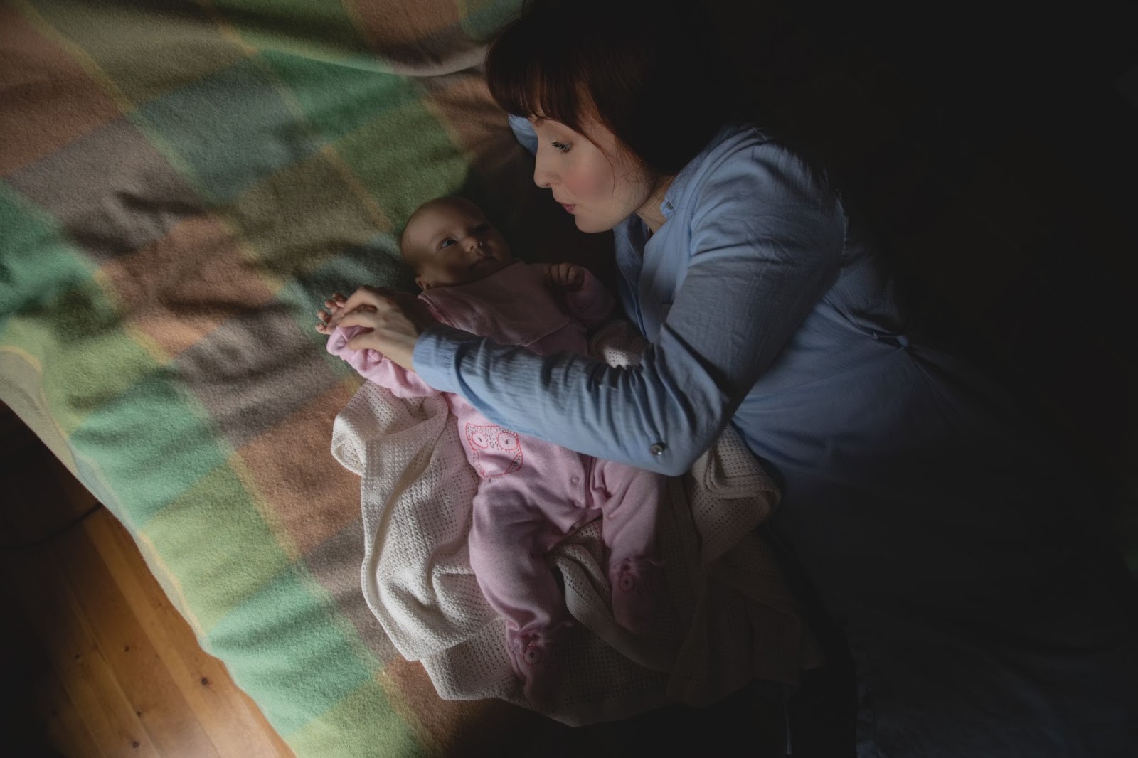 Tips for new parents:- A mom is lying beside her newborn child to make her fall asleep.