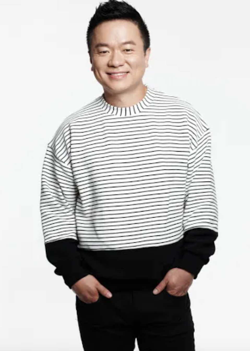 A picture of Comedians Kim Tae Gyun on a black jean trouser and a white and black stripe sweater with his hands in his pocket 